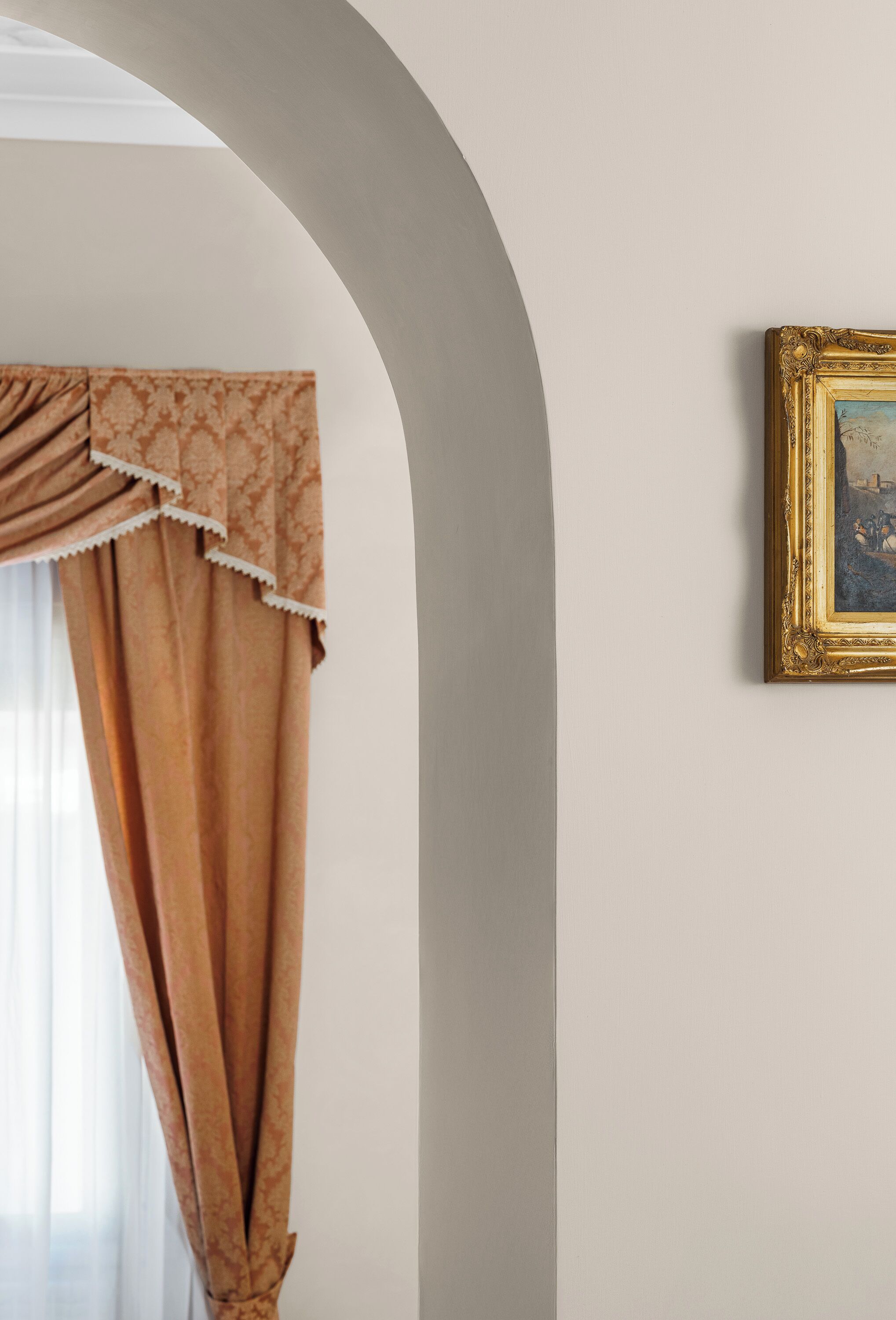A room with a window, a curtain, and a framed picture on the wall.