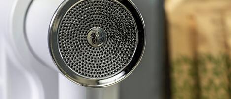 A white hair dryer mounted on a wall with a blurred background.