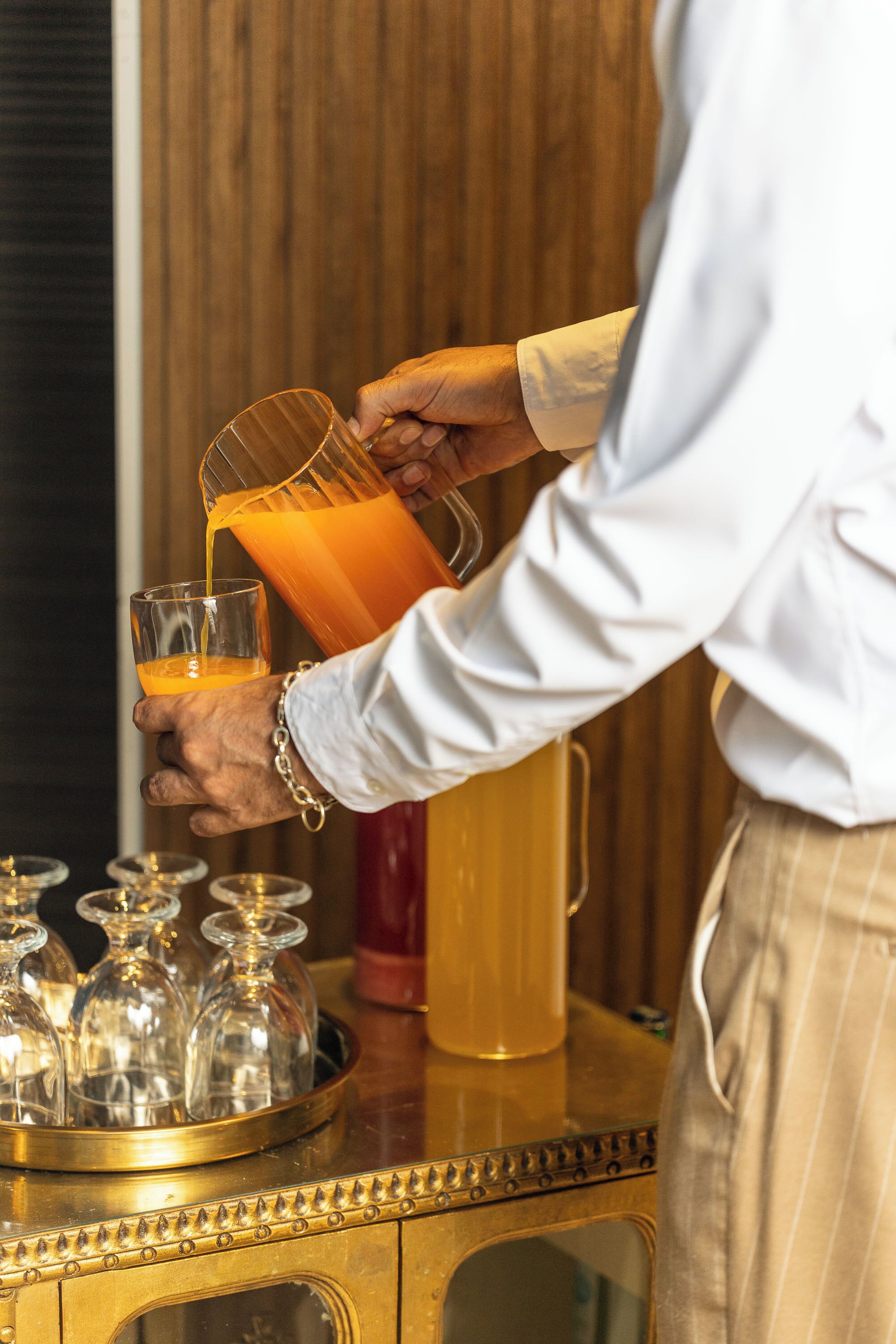 A person pouring orange juice into a glass.