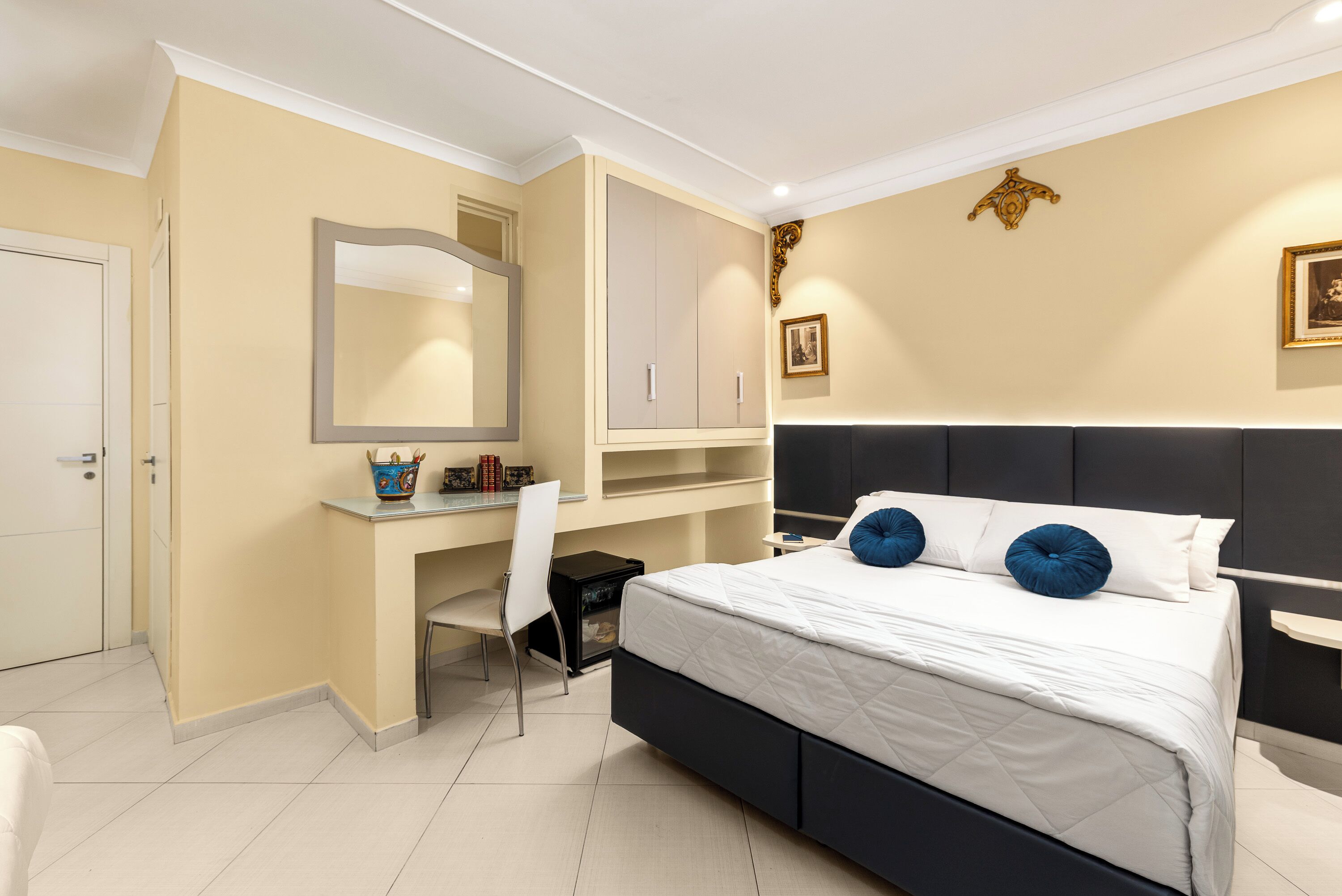 A bedroom with a bed, a desk, a chair, a wardrobe, and a mirror.