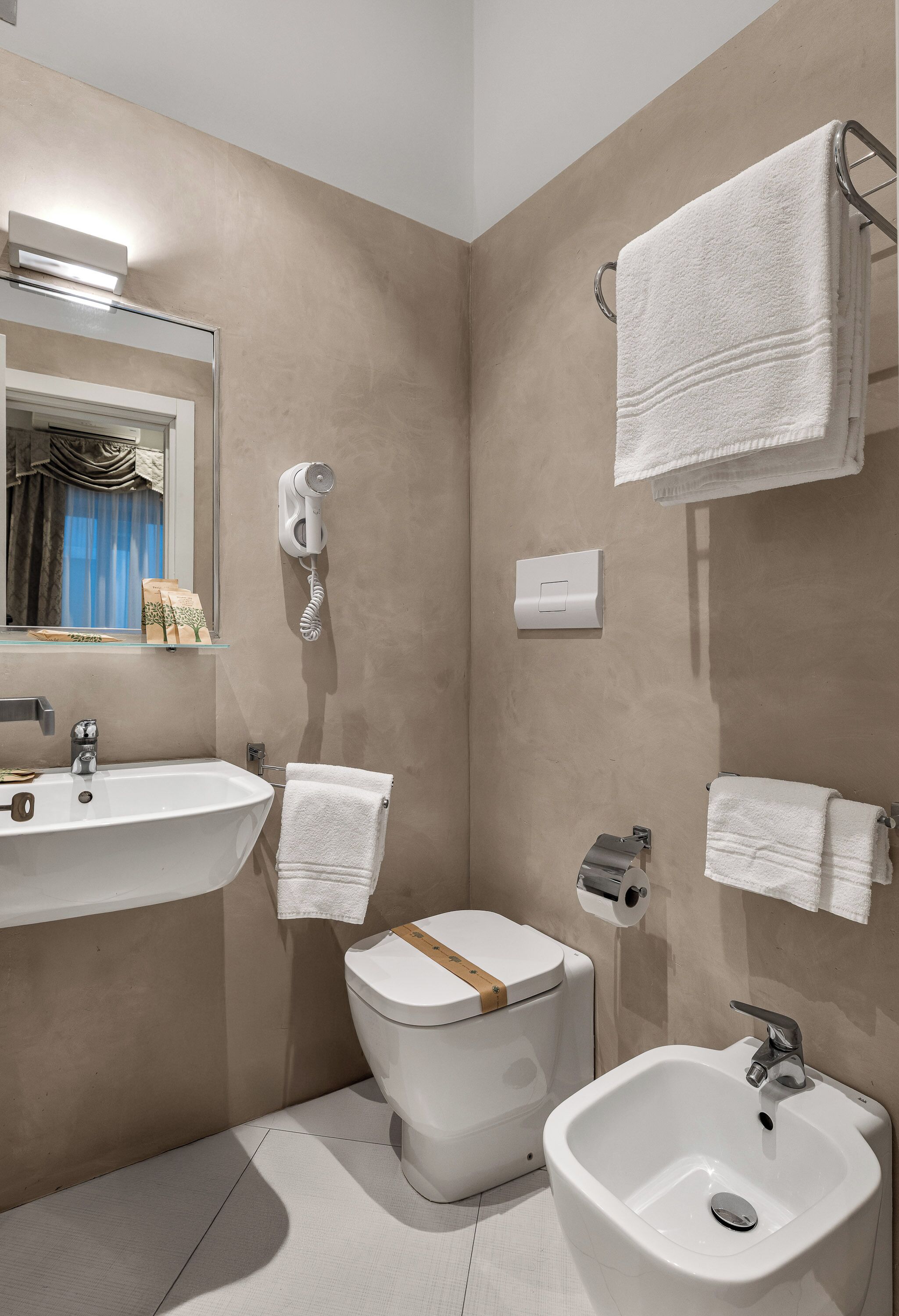 A modern bathroom with a sink, bidet, and towel rack.