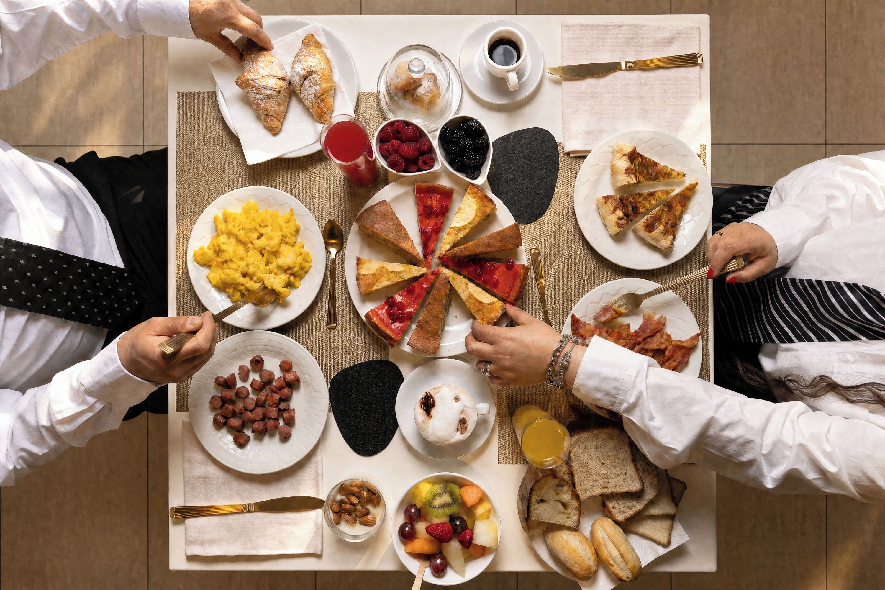 A breakfast setting with various food items and utensils on a table.