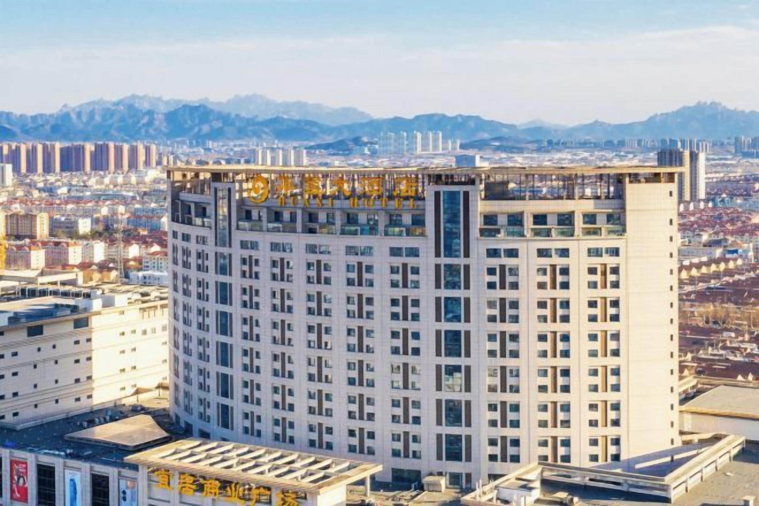 A multi-story hotel with a prominent sign at the top, surrounded by other buildings and a mountainous backdrop.