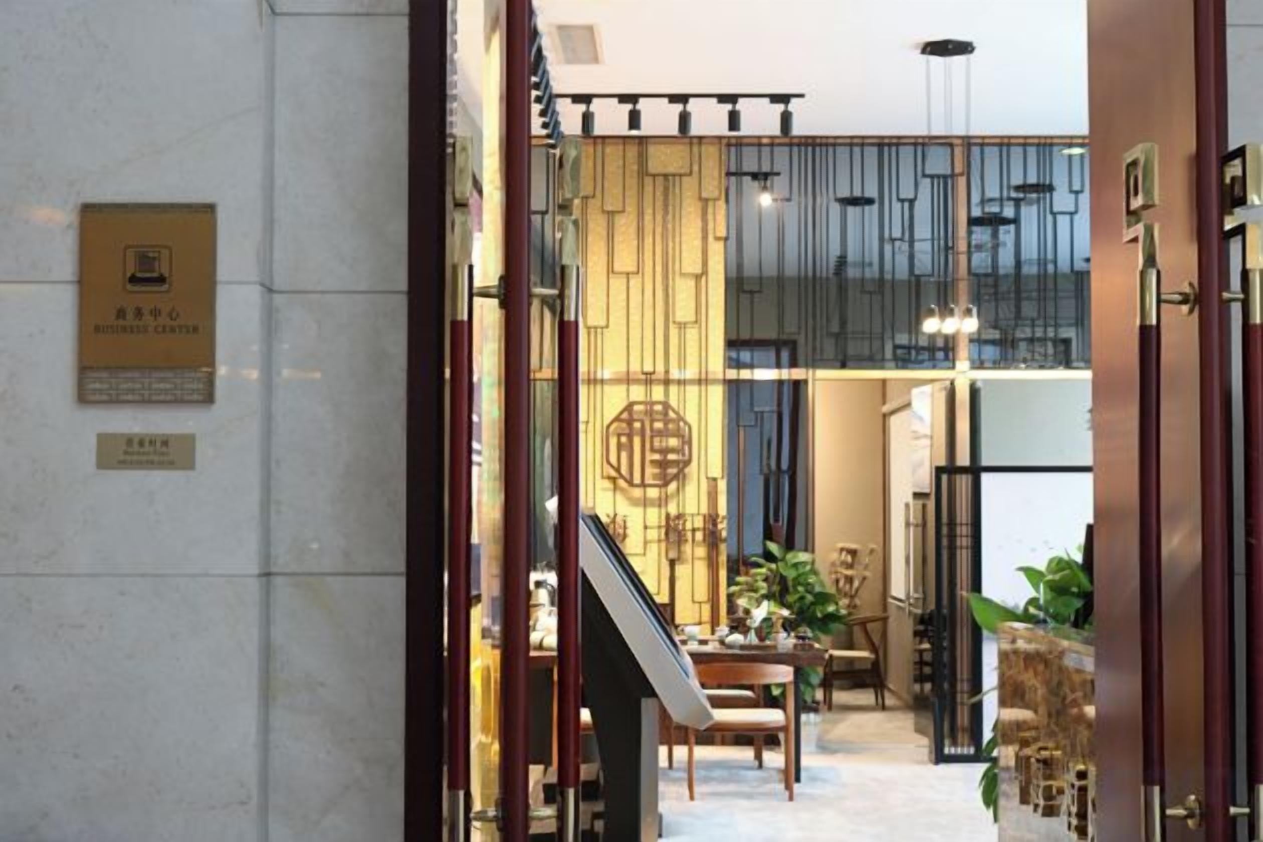 A hotel lobby with a reception desk, a staircase, and a seating area.