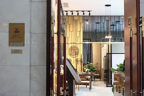 A hotel lobby with a reception desk, a staircase, and a seating area. - Jimo Huaxi Hotel (Qingdao)