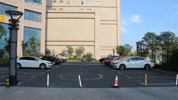 A parking lot with cars, a building in the background, and a clear sky.