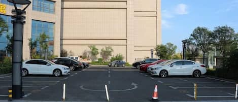 A parking lot with cars, a building in the background, and a clear sky.