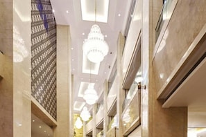 Un intérieur à plusieurs niveaux doté d’un atrium central, de rampes en verre et d’un éclairage moderne.