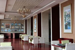 Un hall d’hôtel doté d’un long comptoir d’accueil, de plusieurs tables et de chaises.