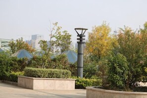 Un espacio exterior con una farola, macetas y edificios al fondo.