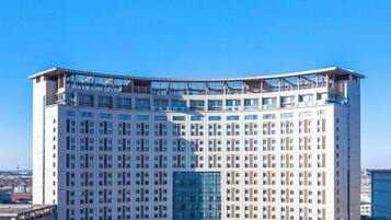A high-rise hotel with a modern architectural design, featuring a central glass facade and multiple balconies.