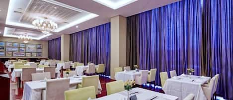 A banquet hall with multiple tables, chairs, and a chandelier.