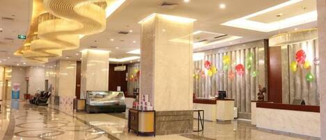 A hotel lobby with a marble floor, a reception desk, and a spiral light fixture.