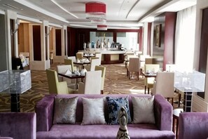 A hotel lobby with a purple sofa, dining area, and a bar. - Jimo Huaxi Hotel (Qingdao)