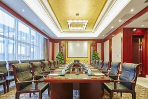 A conference room with a long table, multiple chairs, and a large screen at the front. - Jimo Huaxi Hotel (Qingdao)