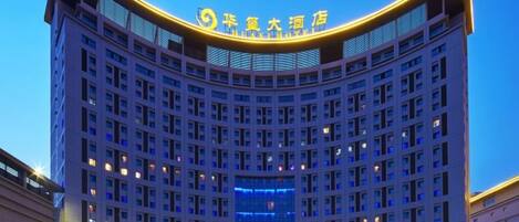 A multi-story hotel with a curved facade and illuminated signage.