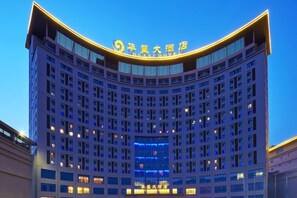 Un hôtel à plusieurs étages, doté d’une façade incurvée et d’une enseigne lumineuse.