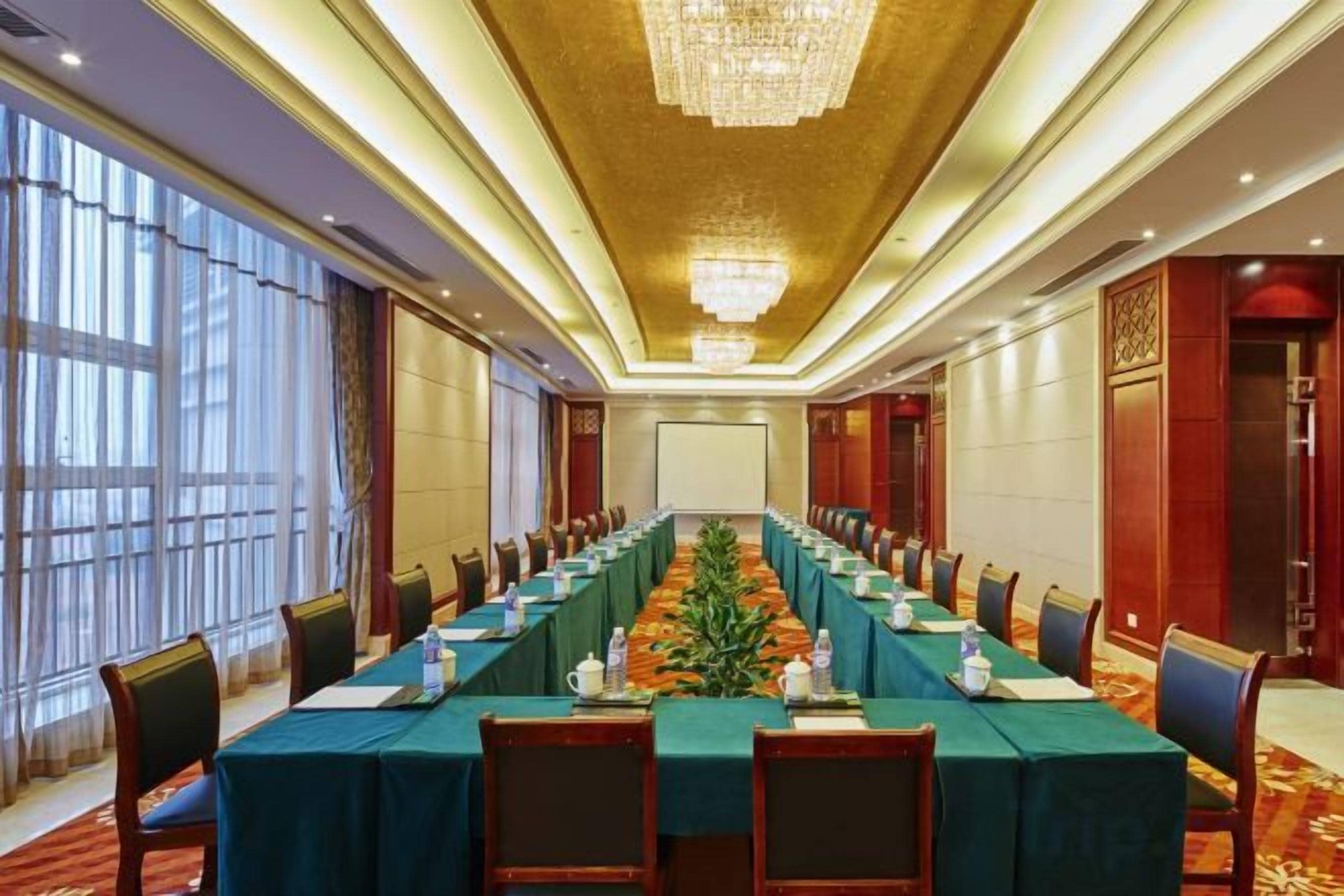 A conference room with a long table, chairs, and a projector screen.