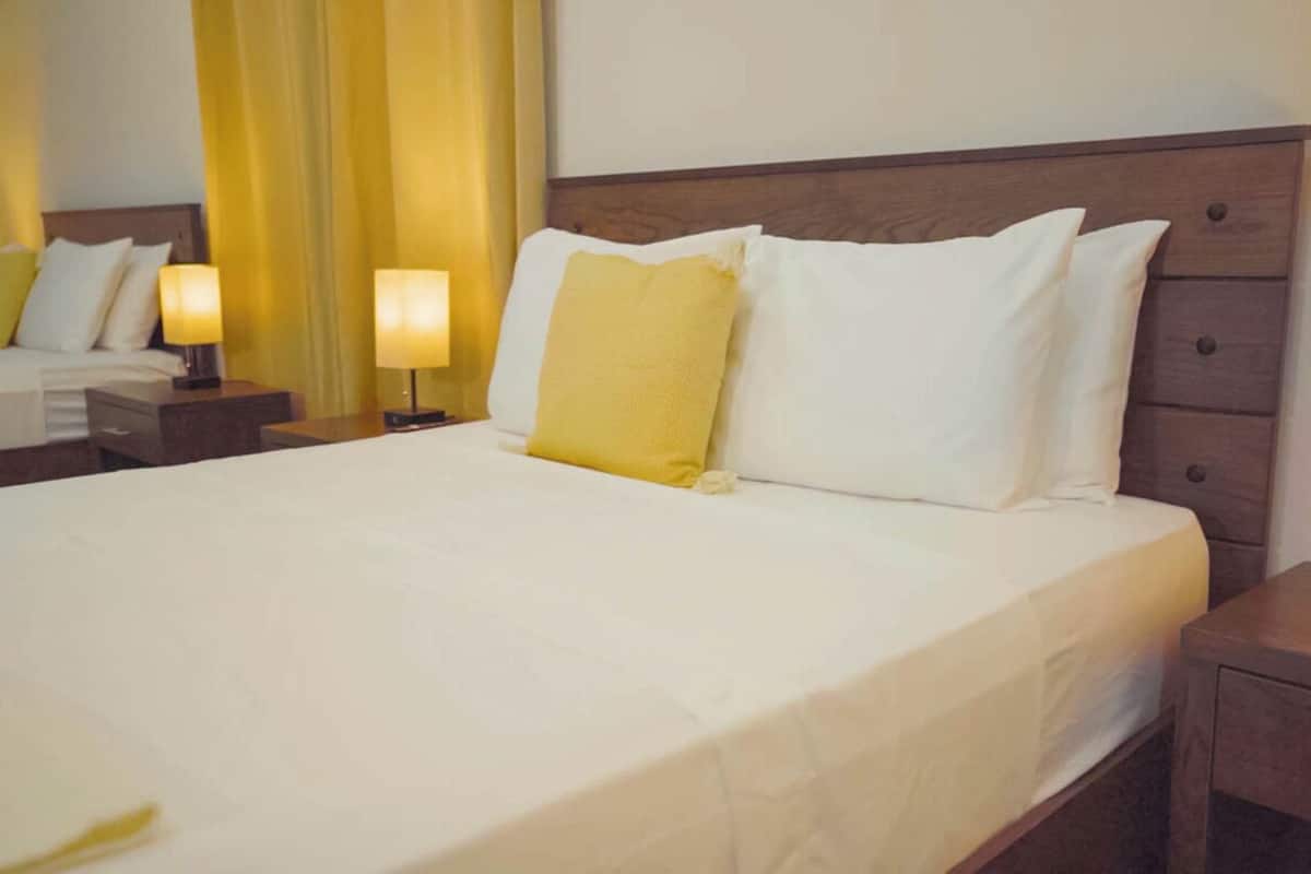 A hotel room with a large bed, two bedside tables, and a nightstand.