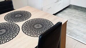 Eine kleine Küche mit weißen Schränken, einer schwarzen Arbeitsplatte und einer hängenden Pendelleuchte.