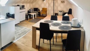 Ein modernes, kompakter Wohnraum mit Essbereich, Küche und schrägverdeckelter Decke.