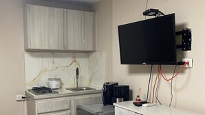 A compact kitchen with a built-in stove, a coffee maker, and a TV mounted on the wall. - Beach Apartments Nabusimake (Santa Marta)