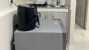 A compact kitchen with white cabinets, a countertop, a sink, a stove, and a black appliance on the counter. - Beach Apartments Nabusimake (Santa Marta)