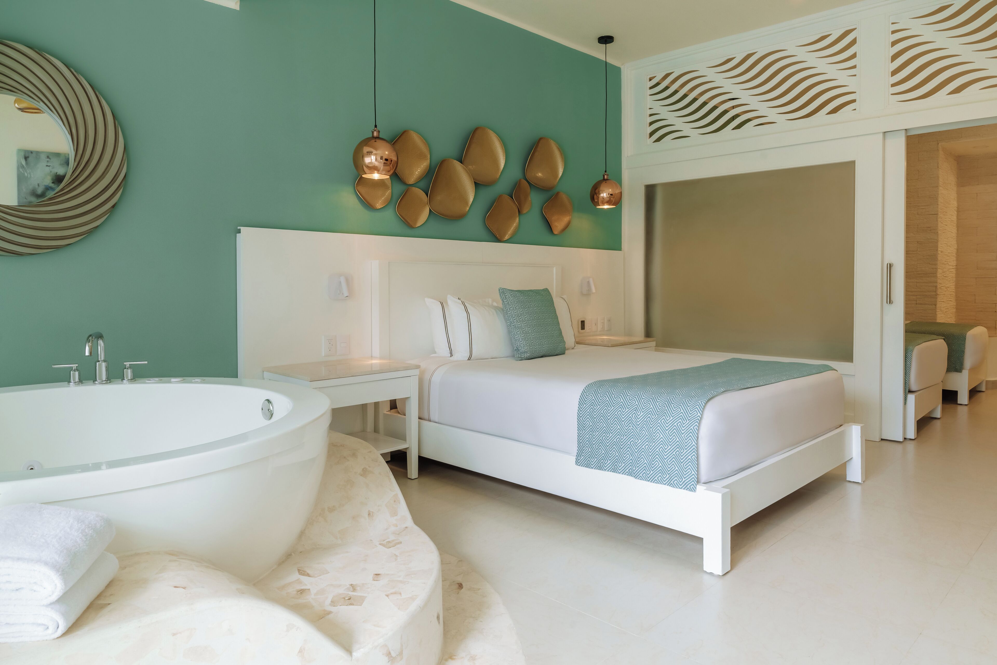 Una camera da letto moderna con una vasca da bagno ampia, un letto con biancheria bianca e un lampadario a parete.