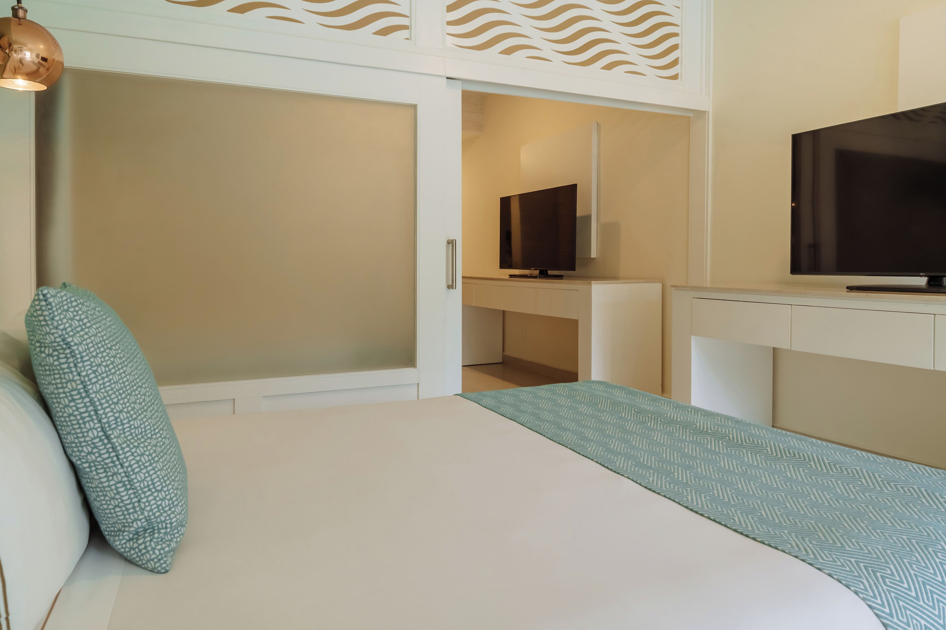 A modern hotel room with a bed, a TV, and a desk.