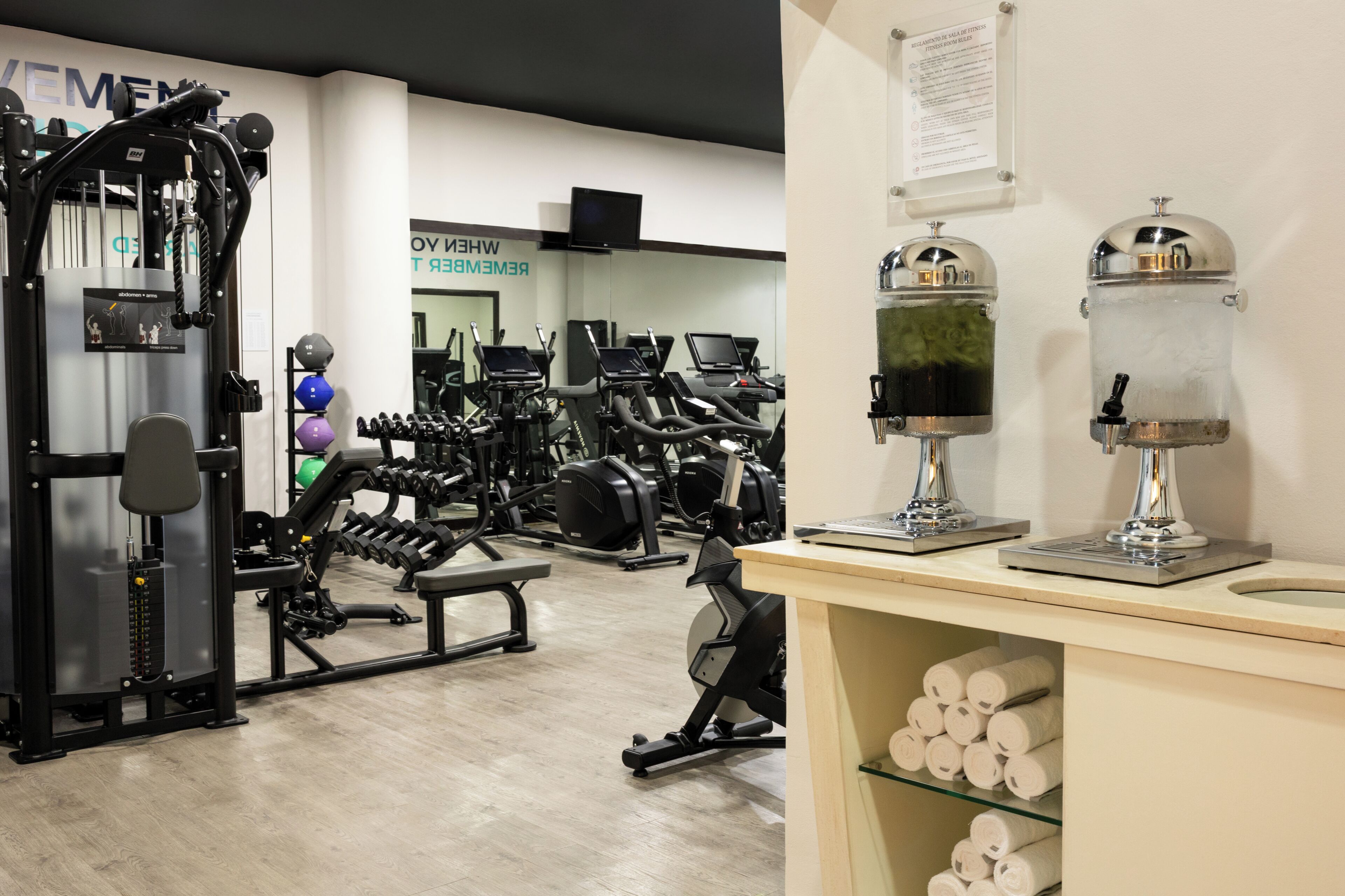 Een sportschool met trainingsapparatuur, een spiegel en een bord aan de muur.