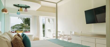 A modern hotel room with a large bed, a balcony with a view, a flat-screen TV, and a dining area.
