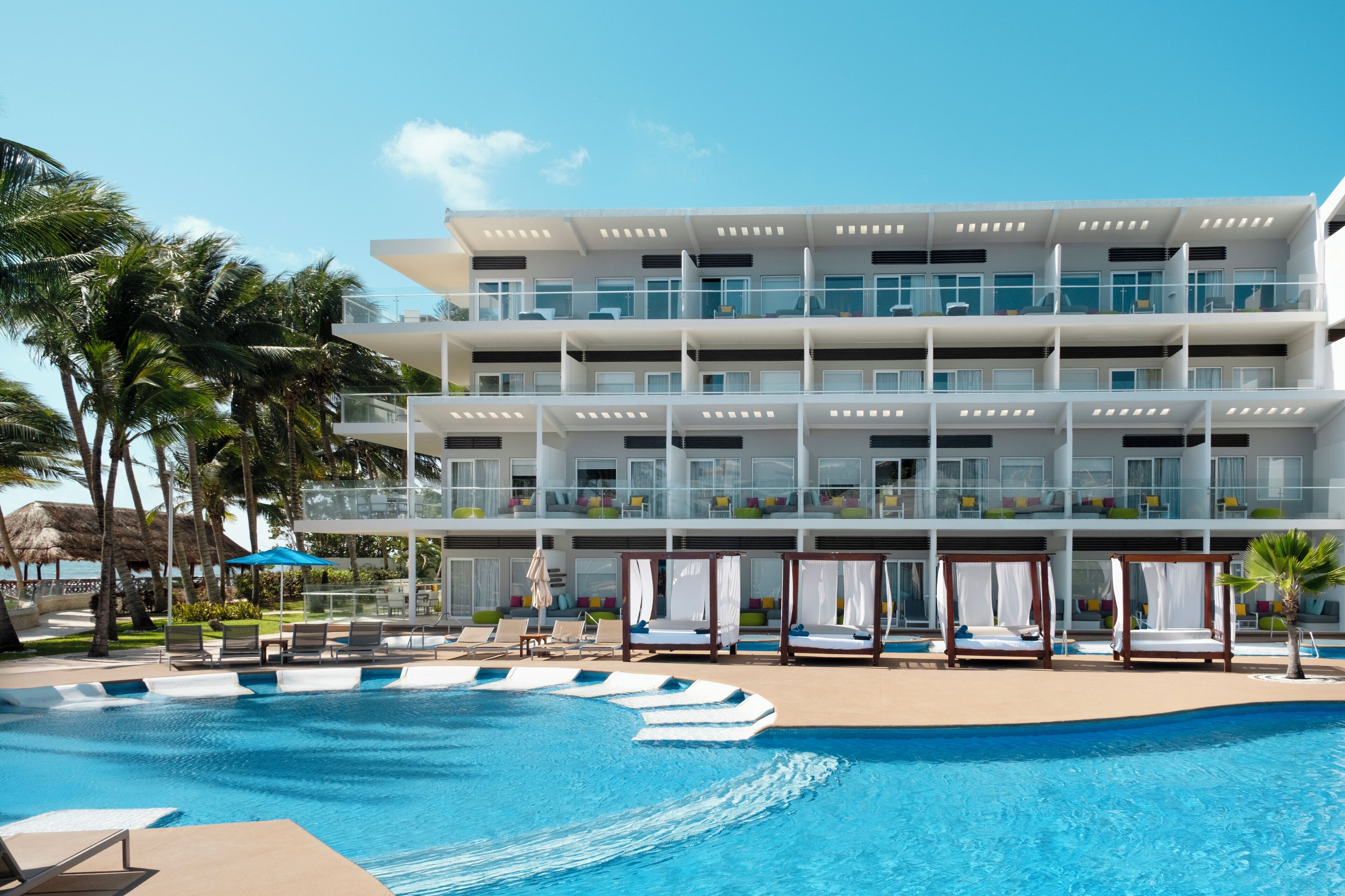 Ein modernes Hotel mit Pool, mehreren Balkonen und Sitzbereichen im Freien.