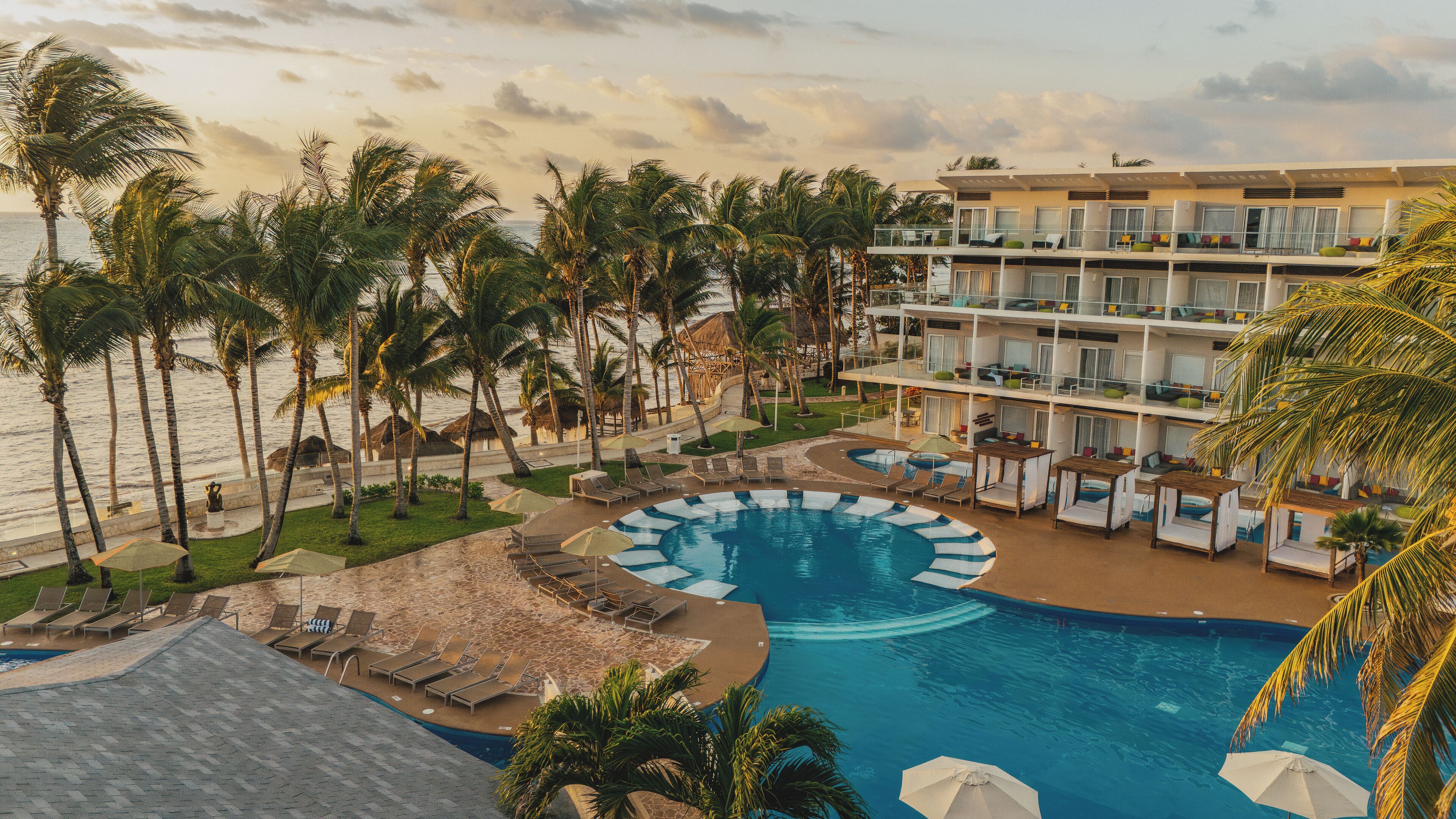 A resort with a pool, palm trees, and a beach.