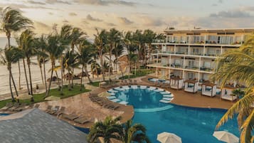 A resort with a pool, palm trees, and a beach.