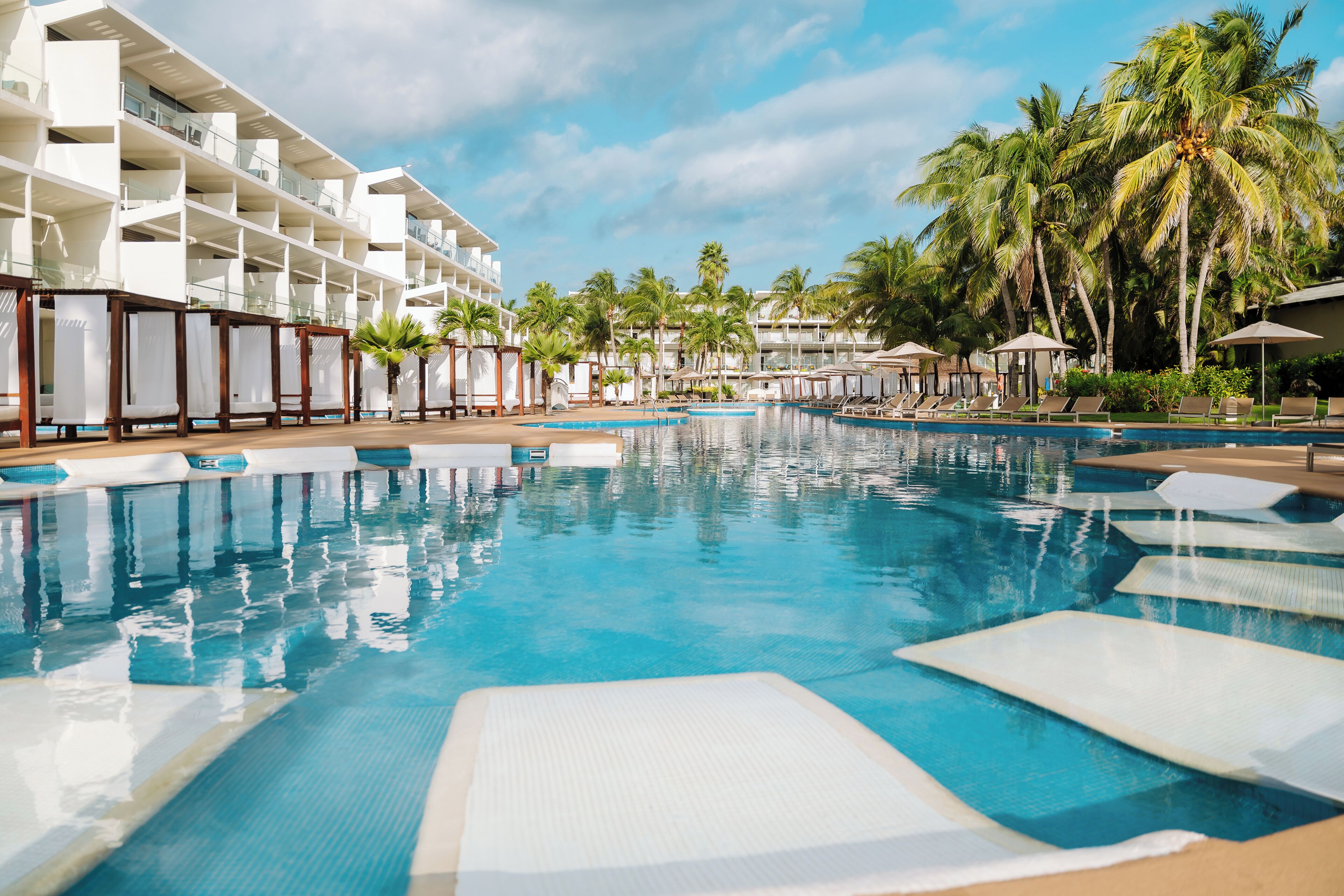 Un espace piscine d’hôtel comprenant plusieurs chaises longues et une grande piscine.