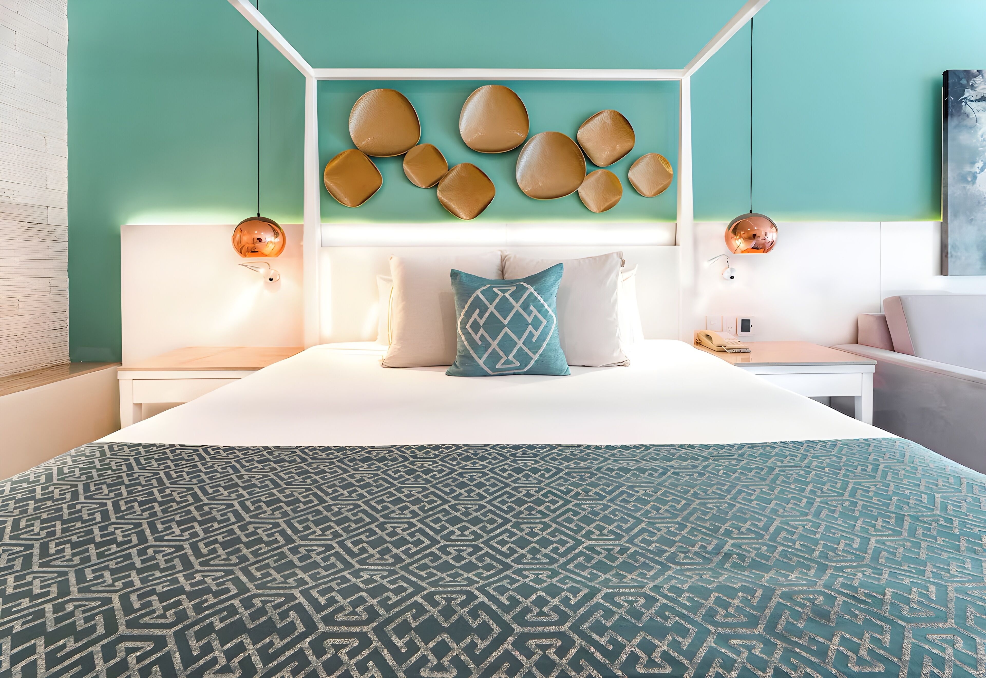 A modern bedroom with a geometric patterned bedspread, a white canopy bed, and a wall-mounted light fixture with a circular design.