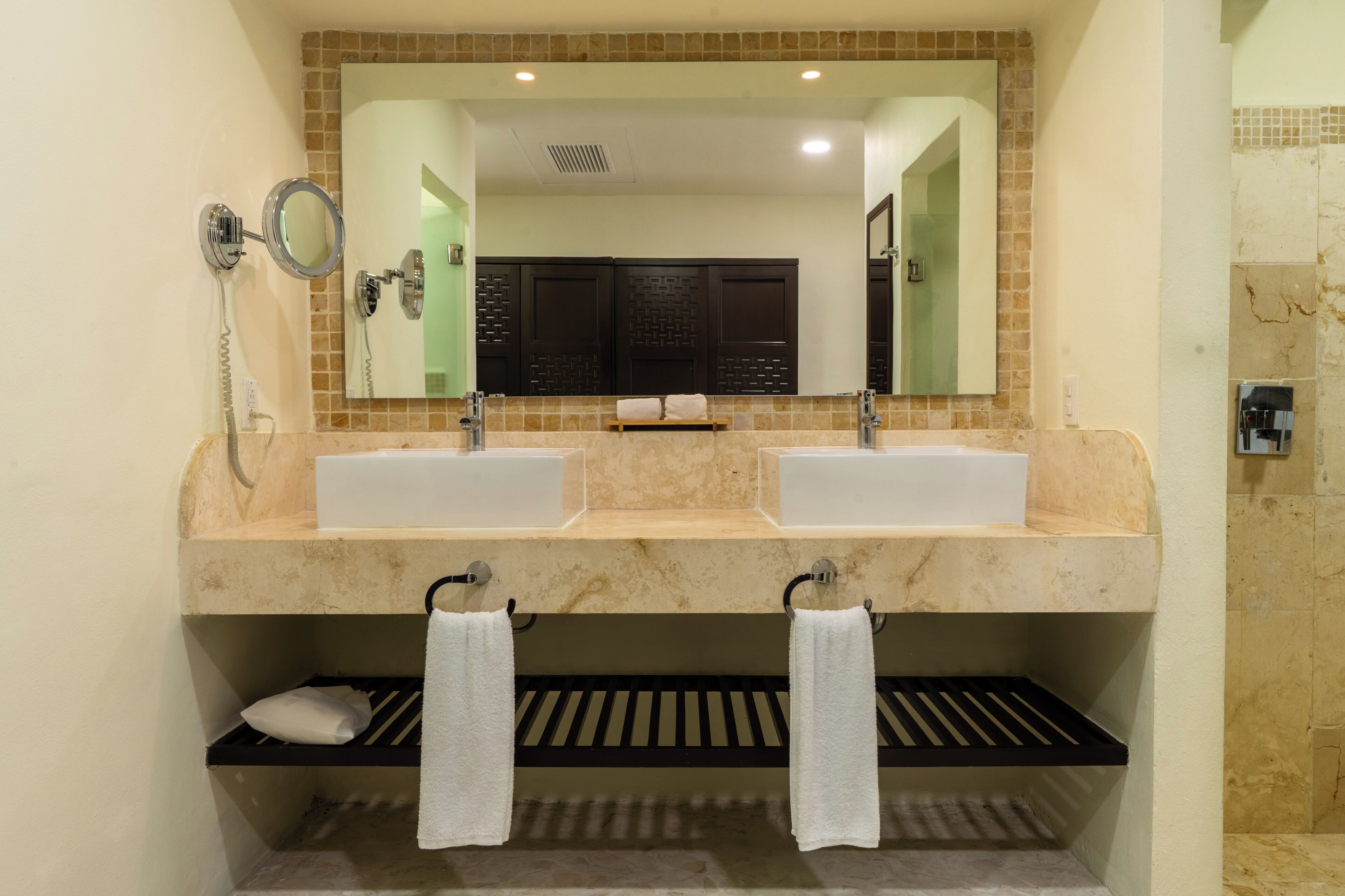 Un baño con dos lavabos, un espejo grande y un perchero para toallas.