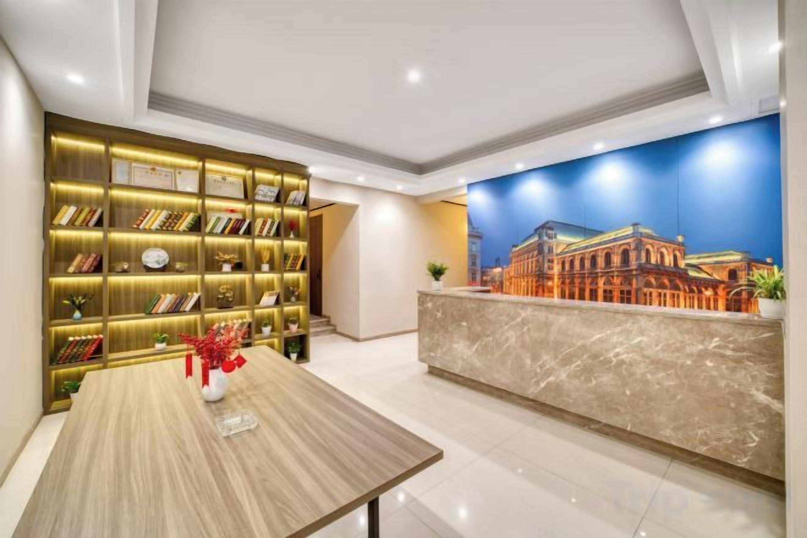 A hotel reception area with a marble counter, a bookshelf, and a mural of a building.