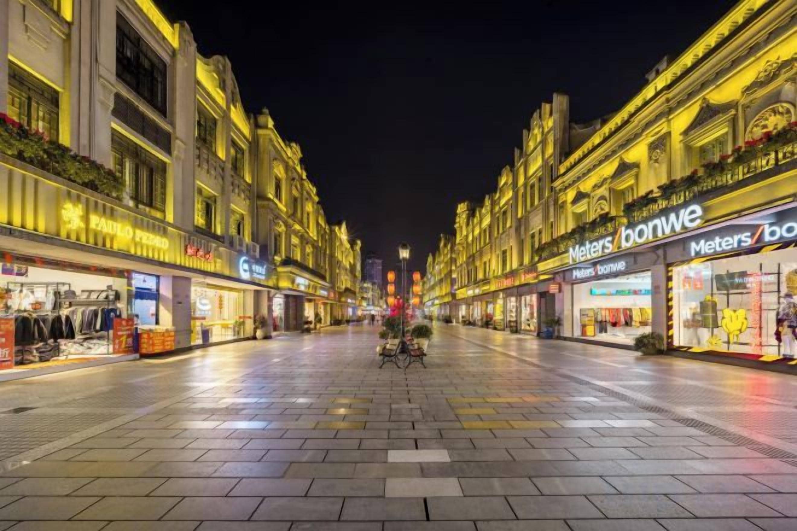 Una calle nocturna con escaparates iluminados, incluyendo un letrero visible que dice 'Meters'.