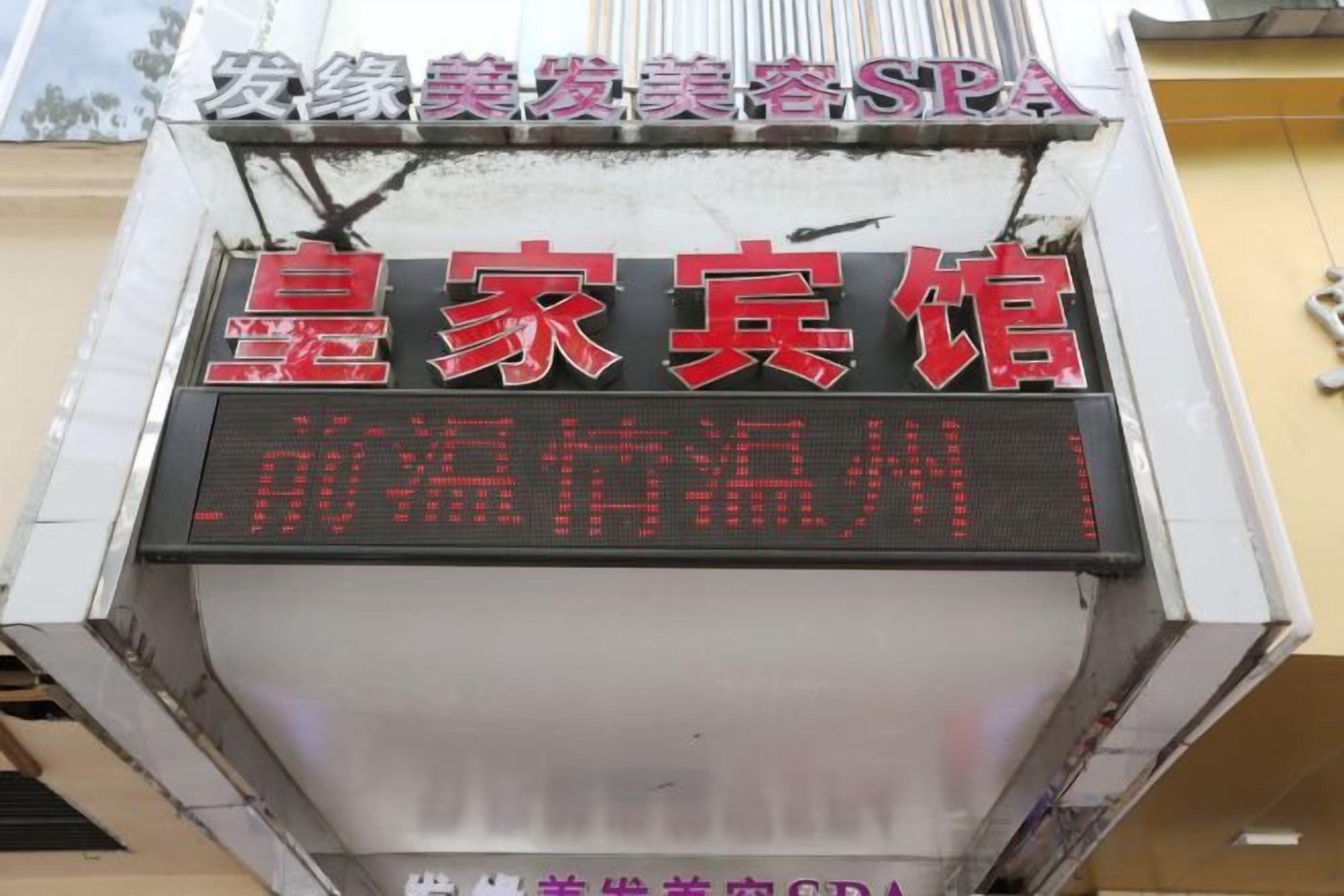 A hotel sign with red and white text, a digital display, and a small window.