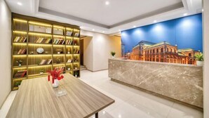 Una hall d'albergo con reception, un bancone in marmo e una libreria con scaffali illuminati.