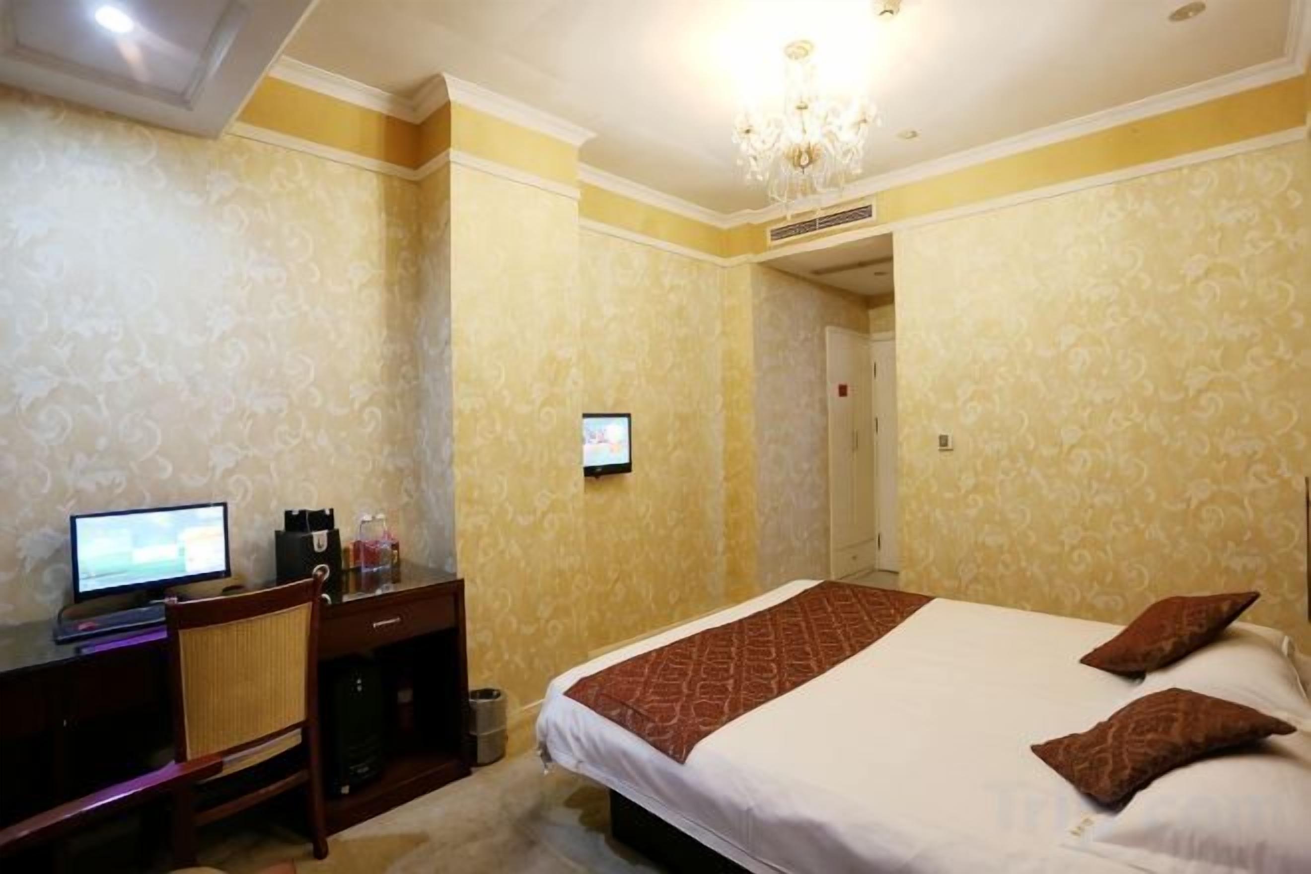 A hotel room with a bed, a desk with a computer, and a television.