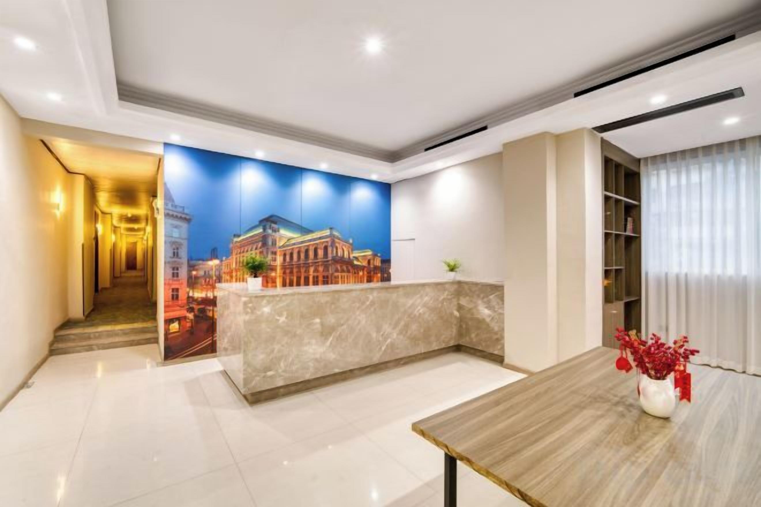 A hotel lobby with a reception desk, a large mural, a staircase, and a dining area.