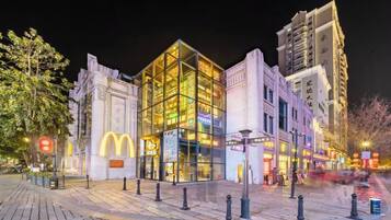 A modern building with a glass facade, a McDonald's logo, and a paved plaza with bollards.