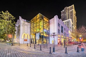 Un bâtiment moderne avec une façade en verre, le logo de McDonald's, et une place pavée agrémentée de bornes.