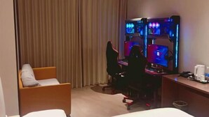 Una camera d'albergo con un letto, una scrivania con un computer, una sedia e una tenda.