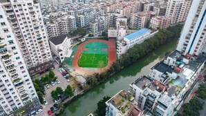 Zona residenziale con edifici alti e un campo sportivo centrale circondato da palazzi.