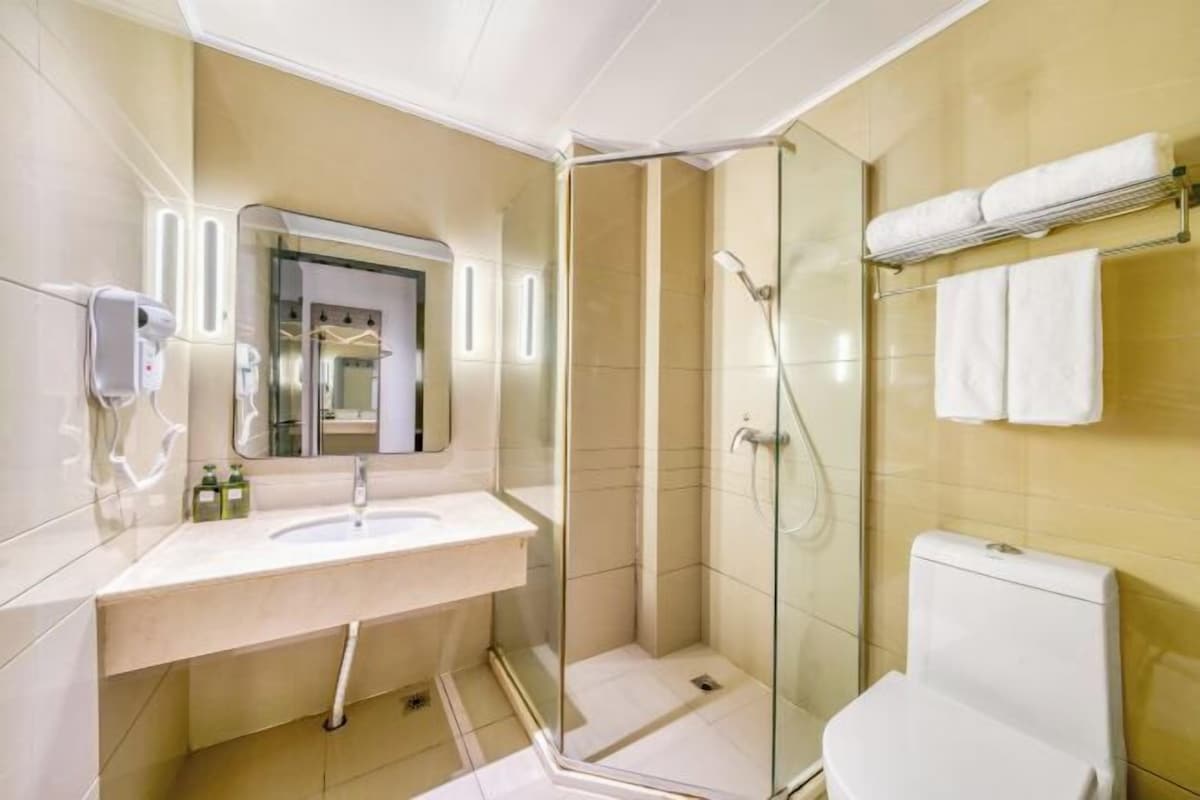 A modern bathroom with a glass-enclosed shower, a white sink, and a toilet.