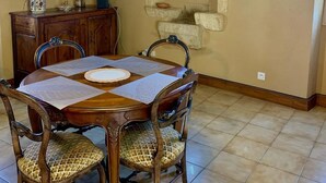 A dining area with a wooden table, four chairs, a cabinet, and a stone wall.