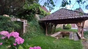 A garden with a gazebo, a stone wall, and pink flowers.